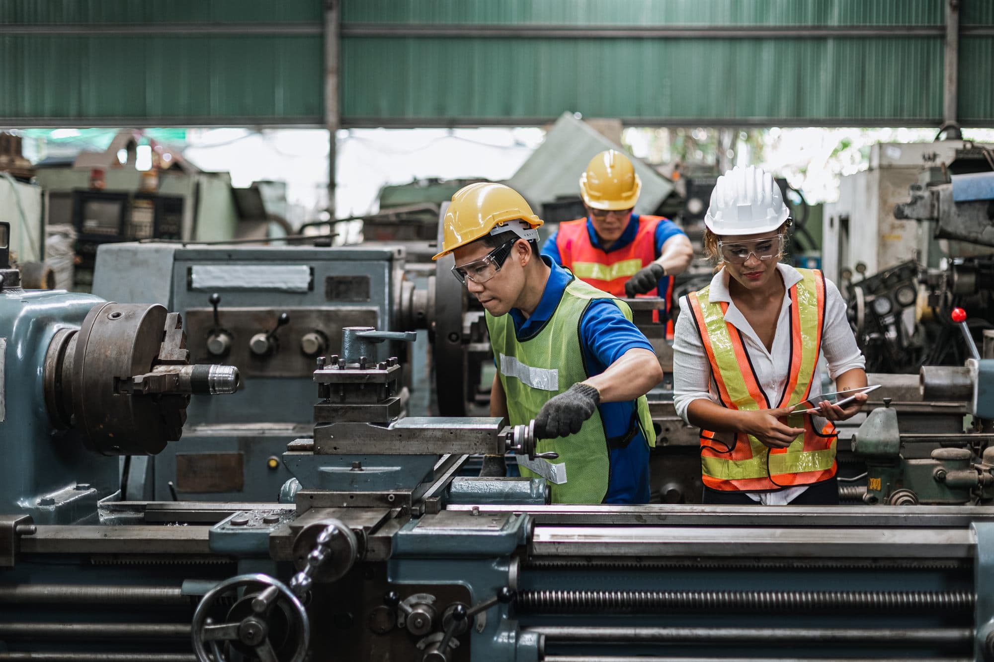 Plant-floor team operating industrial machinery while reviewing data on a tablet